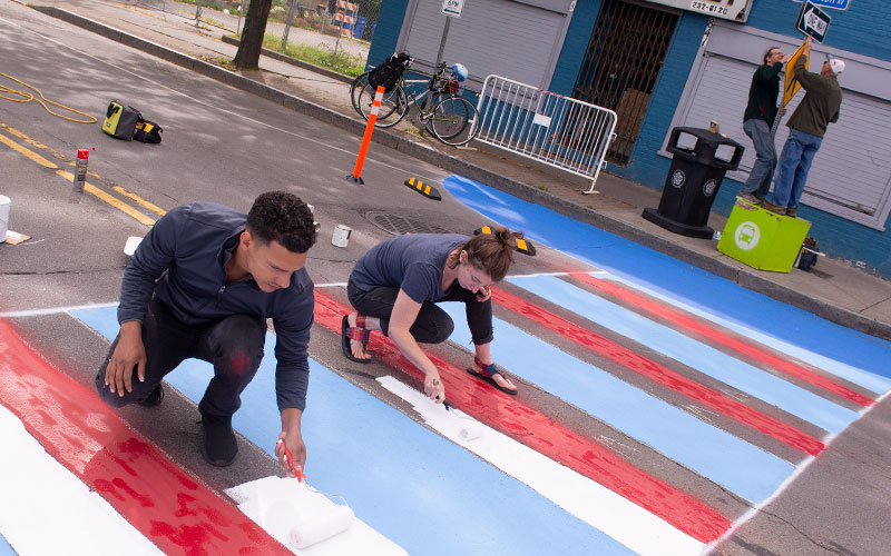 Santos Cruz y Anna Keller pintan un cruce de peatones mientras Scott Wagner y Frank Staropoli instalan un letrero de cruce de peatones en la Avenida North Clinton de Rochester el 29 de septiembre como parte del programa Complete Streets Makeover.
